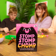 Load image into Gallery viewer, Stomp Stomp Chomp card game box on a table with people playing in the background