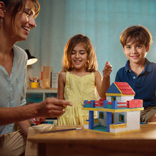 Load image into Gallery viewer, Woman and two children playing with a toy house at a table.
