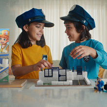 Load image into Gallery viewer, Two children playing with a toy city set, wearing blue hats.
