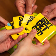 Load image into Gallery viewer, Hands holding yellow cards with 'Don't Get Got' text on a wooden surface
